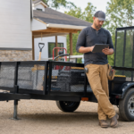 Contractor reviewing a job plan beside a utility trailer